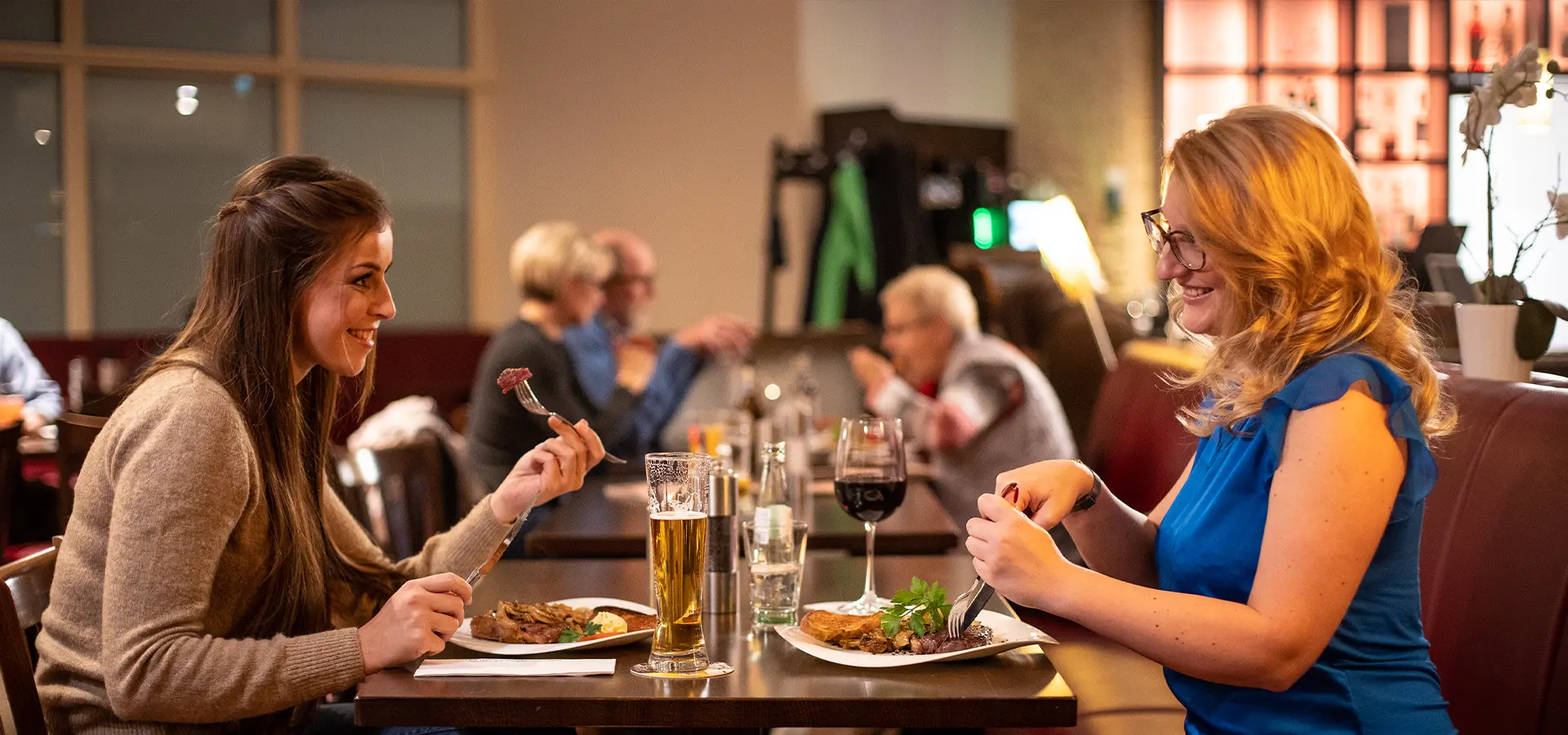 zwei Frauen sitzen sich gegenüber und schneiden ihr Essen