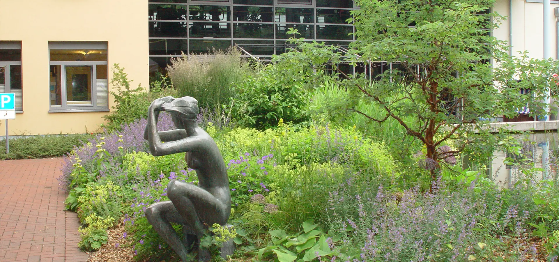 Grüne Wiesenfläche mit einer Bronzestatur einer Frau