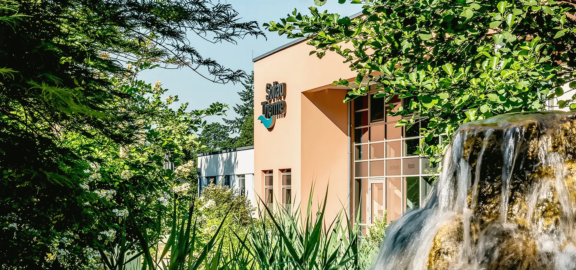 Außenansicht mit Bäumen und Soltau Therme Logo an der Fassade