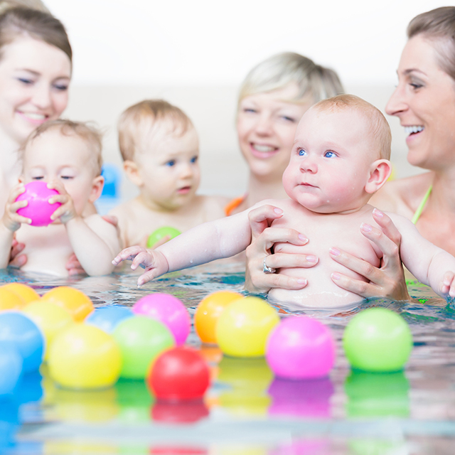 Mütter und Babys spielen mit Bällen im Lehrschwimmbecken