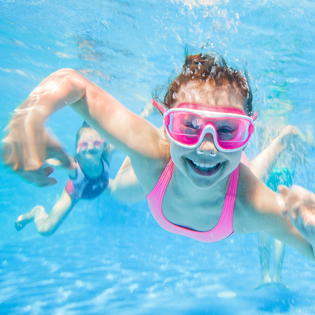 Mädchen tauchen im Schwimmbad und lächeln in die Kamera